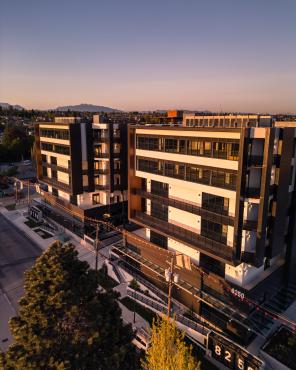 Twin modern buildings, seen from across the street at roof level. The building on the right is numbered 8250. Mountains can be seen in the distance.